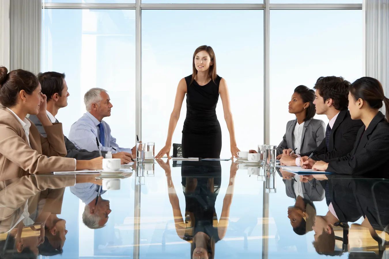 A leader briefs her executive team at a glass conference table