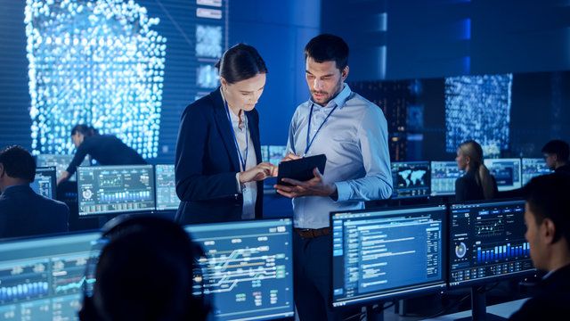 Two engineers review a tablet in a security operations center