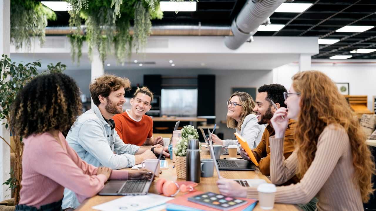 Colleagues laugh together while working around a shared table